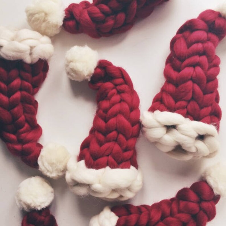 May include: A group of red and white knitted Santa hats with a braided design. The hats are made of a soft, fluffy yarn.
