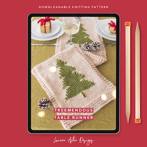 May include: A digital tablet displaying a knitting pattern for a Christmas table runner with a green knitted Christmas tree design. The text on the screen reads "Tremendous Table Runner" and "Lauren Aston Designs". Two wooden knitting needles are shown on the right side of the image.