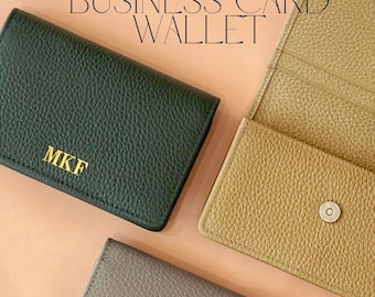 May include: Three RFID-protected business card wallets in dark green, tan, and gray. The dark green wallet features gold-colored initials MKF. The tan wallet is open, revealing an interior pocket and a silver-colored magnetic snap closure.