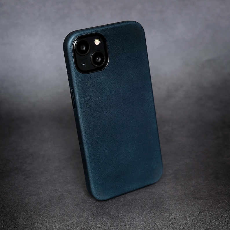 Pu&ograve; includere: Una custodia per telefono di colore blu scuro con una finitura testurizzata. La custodia ha un ritaglio per l'obiettivo della fotocamera sul retro.