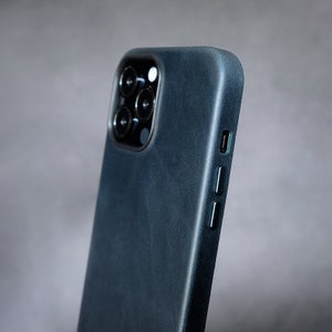 Pu&ograve; includere: Una custodia per telefono di colore blu scuro con una finitura testurizzata. La custodia ha un ritaglio per l'obiettivo della fotocamera e un ritaglio per la porta di ricarica.