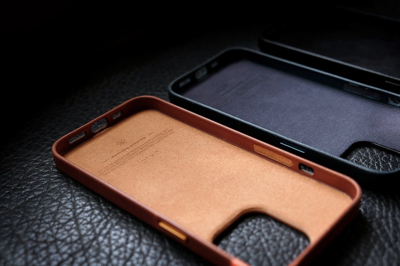 Pu&ograve; includere: Due custodie per telefono, una in pelle marrone e una in pelle nera. La custodia in pelle marrone ha una texture sottile e un piccolo logo all'interno. La custodia in pelle nera ha una superficie liscia.