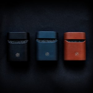 May include: Three leather cases in black, dark blue, and brown with a white logo that says "UNC" with a cross in the middle.