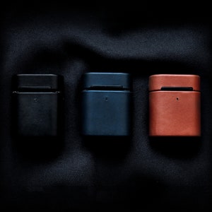 May include: Three small rectangular cases made of leather in black, blue, and brown.