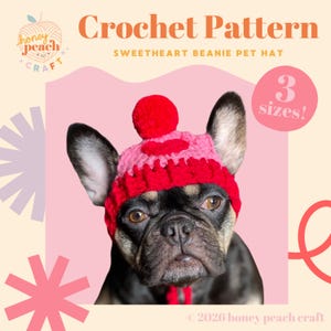 Op de afbeelding: Een zwarte en bruine Franse Bulldog draagt een rood en roze gehaakte Sweetheart Beanie Pet Hat met een pompon. De afbeelding bevat de tekst "Crochet Pattern" en "3 maten!" op een roze achtergrond. Het Honey Peach Craft-logo is zichtbaar.