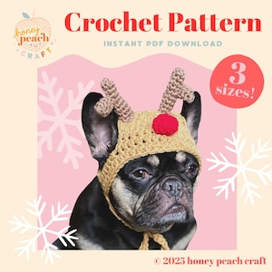 Peut inclure: Un bouledogue français noir et beige portant un chapeau de renne crocheté avec des bois et un pompon rouge. Le chapeau est beige et le fond est rose avec des flocons de neige. Le texte indique "Crochet Pattern" et "3 sizes!"