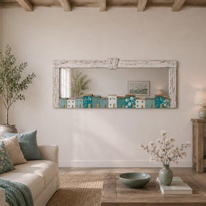 May include: A rectangular wall mirror featuring a distressed white wooden frame. The bottom edge of the mirror is decorated with a row of small, colourful house-shaped blocks in shades of teal, blue, and white, some featuring floral patterns.