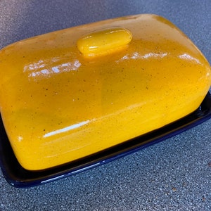 Unique handmade yellow butter dish lid on a rich royal blue dish