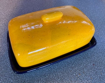 Einzigartiger handgefertigter gelber Butterdose auf einer königsblauen Schale