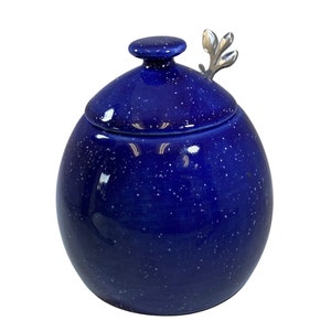 May include: A blue ceramic sugar bowl with a white speckled glaze and a silver leaf-shaped lid.