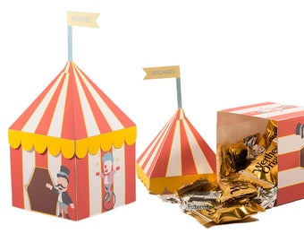 Peut inclure: Deux boîtes en forme de chapiteau de cirque rayées de rouge et de blanc avec des bordures jaunes. Une boîte est ouverte et remplie de chocolats enveloppés de papier d'or. La boîte porte l'inscription "Werther's Original". La boîte fermée a un clown sur un monocycle et un maître de cérémonie avec une moustache imprimés dessus. Le texte "MICHAEL" est imprimé sur un drapeau au sommet de chaque boîte.