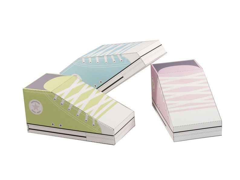 May include: Three paper shoe boxes in the shape of high-top sneakers. The boxes are decorated with a white and light blue stripe pattern, a white and green stripe pattern, and a white and pink stripe pattern.