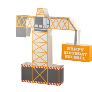 May include: A yellow and orange construction crane party favour box with a grey base and a separate box that says "Happy Birthday Michael".