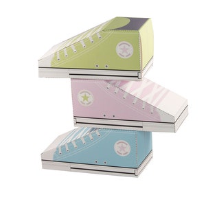 May include: Three cardboard boxes shaped like sneakers stacked on top of each other. The top box is green, the middle box is pink, and the bottom box is blue. Each box has a white star on the side.