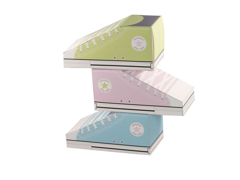 May include: Three cardboard boxes shaped like sneakers stacked on top of each other. The top box is green, the middle box is pink, and the bottom box is blue. Each box has a white star on the side.