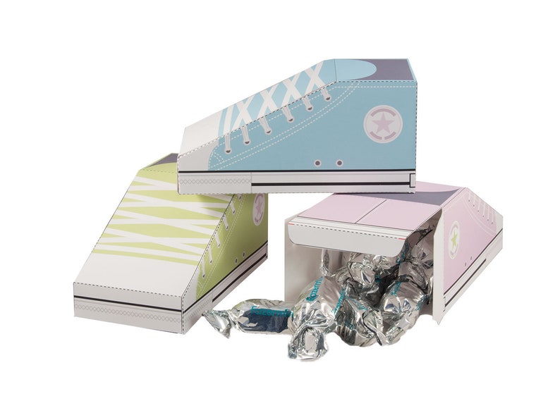 May include: Three cardboard shoe-shaped boxes, one blue, one green, and one pink, with a white star on each. The pink box is open and filled with silver wrapped candies.