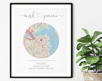 May include: A white framed print featuring a map of Boston, Massachusetts. A red heart pinpoints the location of Ducali Pizzeria, where the couple got engaged on 21 August 2020. The names "mark & gemma" are written in cursive at the top of the print.
