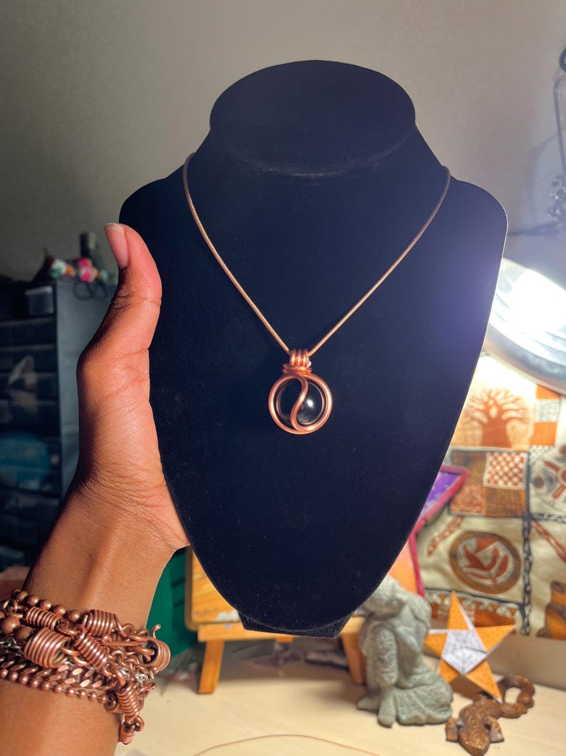 May include: A copper wire wrapped pendant necklace with a black yin yang stone.