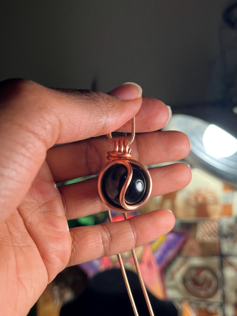 May include: A copper wire wrapped pendant necklace featuring a black yin yang stone.