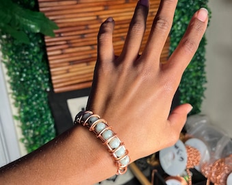 May include: A copper wire wrapped bracelet with light green gemstone beads.