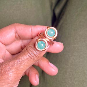 Puede incluir: Un anillo doble con dos piedras verdes engastadas en alambre de cobre.