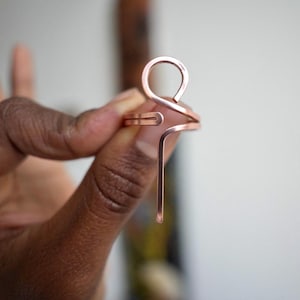 Op de afbeelding: Een ring van koperdraad met een gestileerd ontwerp dat lijkt op een ankh-symbool.