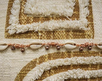 Può includere: Un braccialetto in filo di rame con conchiglie bianche e perline di rame.