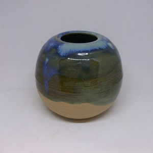 May include: A round ceramic vase with a blue, green and brown glaze. The vase has a wide opening and a rounded bottom.