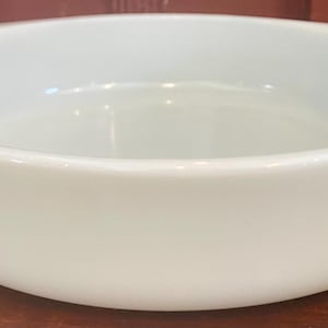 May include: A white, round serving bowl with two small handles on either side. The bowl has a smooth, glossy finish and is made of ceramic. The bowl is suitable for serving side dishes, salads, or desserts.