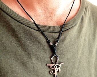 Könnte beinhalten: Eine silberne Ankh-Halskette mit einem Horus-Augen-Design.