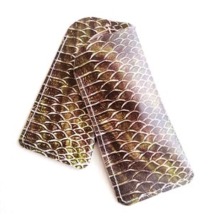 Puede incluir: Dos fundas de teléfono de cuero con estampado marrón y verde con borde cosido.
