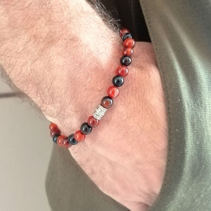 Puede incluir: Un brazalete de cuentas con piedras de ágata roja y negra y una cuenta espaciadora de plata.