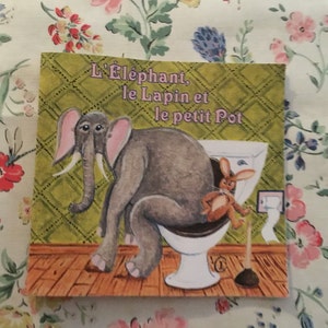 May include: A children's book cover with a green background and a white toilet. An elephant is sitting on the toilet with a rabbit sitting next to it. The title of the book is "L'Elephant, le Lapin et le petit Pot".