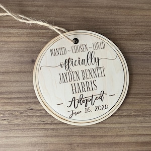 May include: A round wooden ornament with the text "WANTED~CHOSEN~LOVED officially JAYDEN BENNETT HARRIS -Adopted- June 16, 2020".
