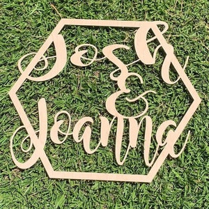 May include: A wooden hexagonal sign with the names Josh and Joanna written in cursive script, with an ampersand symbol between the names.