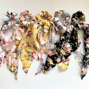Puede incluir: Seis coleteros con estampado floral y pañuelos adjuntos. Los coleteros presentan una variedad de colores, incluyendo blanco, rosa, amarillo y negro, cada uno adornado con un patrón floral diferente. Los pañuelos están hechos de tela suave y están diseñados para atarse o usarse como un acento decorativo.