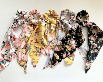 Puede incluir: Seis coleteros con estampado floral y pañuelos adjuntos. Los coleteros presentan una variedad de colores, incluyendo blanco, rosa, amarillo y negro, cada uno adornado con un patrón floral diferente. Los pañuelos están hechos de tela suave y están diseñados para atarse o usarse como un acento decorativo.