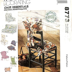 May include: A McCall's Home Decorating sewing pattern envelope 8773 for Chair Essentials. The front features illustrations of five chair cushion styles labeled A through E, with a central image of a wooden chair featuring a fruit-patterned fabric cover.