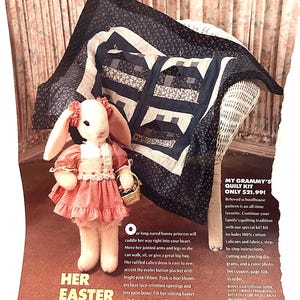 May include: A plush bunny doll in a pink dress with a basket, and a schoolhouse quilt on a wicker chair. The text reads "HER EASTER BEST". The quilt has a navy blue floral pattern and white accents.