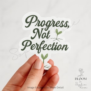 May include: A white sticker with the text "Progress, Not Perfection" in a dark green, cursive font. The sticker features two small green sprout illustrations. The Bloom by Sophia Rose logo is in the bottom right corner.