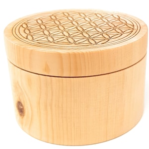 Könnte beinhalten: Eine runde Holzkiste mit Deckel. Der Deckel ist mit einem Laser-geätzten Muster einer Blume des Lebens verziert.