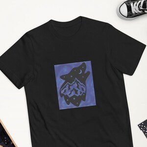 May include: Black t-shirt with a graphic of a wolf howling at the moon with mountains inside its silhouette. The wolf is outlined in white and the background is a gradient of blue and purple.