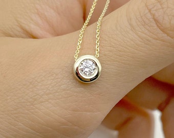 May include: A delicate gold chain necklace with a small round pendant featuring a clear gemstone.