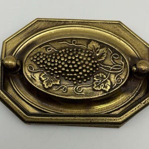 May include: A white ceramic mug with a black handle and the text "But First, Coffee" in a bold, black font. The mug is set against a blurred background, suggesting a cozy setting.