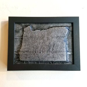 May include: A framed artwork featuring a textured, silver-colored outline of the state of Oregon. The artwork is set against a dark gray background with subtle blue accents.