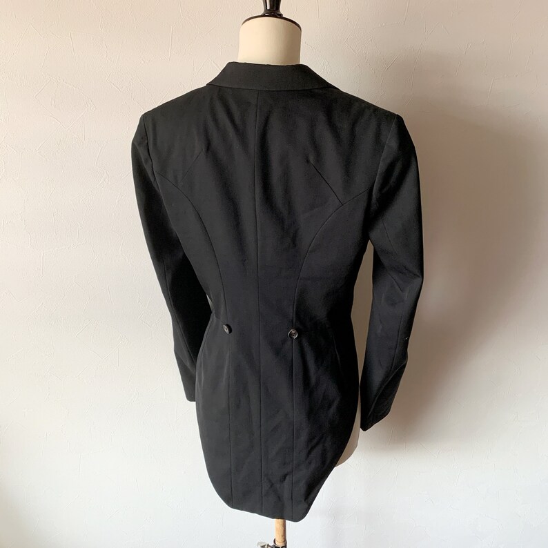 May include: A black tailcoat with a long, pointed back. The coat has a single button closure at the waist and two buttons on the back.