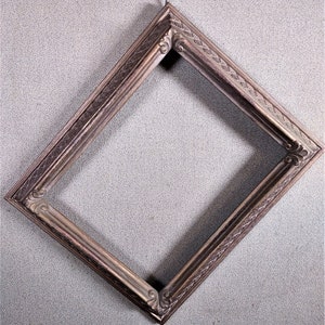 May include: A diamond-shaped picture frame with a brown wood finish and ornate carvings. The frame has a distressed look and is ready to display a special photo or artwork.