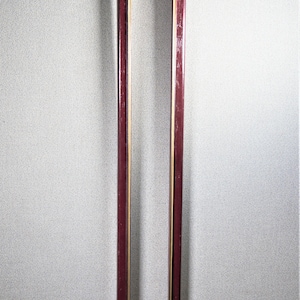 May include: A tall, rectangular picture frame with a dark red wood finish and a thin gold inner border. The frame is empty.