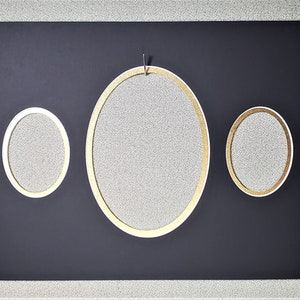 May include: Three oval-shaped picture frames with gold trim on a black background. The largest frame is in the center and the two smaller frames are on either side.