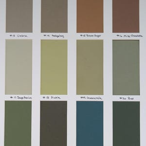 May include: A color swatch card featuring twelve rectangular samples arranged in three rows. The colors include shades of beige, brown, olive, green, and teal. Each swatch is labeled with a number and a name, such as #13 Umbria, #14 Hedgehog, #15 Brown Sugar, #16 Milk Chocolate, #17 Sage Advice, #18 Pickle, #19 Guacamole, #20 Bud, #21 Spinach, #22 Sierra Olive, #23 Real Teal, and #24 Forest Green.